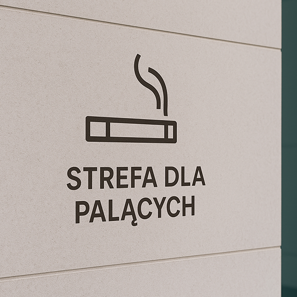 Obraz przedstawia fragment ściany z naklejonym oznaczenie papiera i napisem STREFA DLA PALĄCYCH