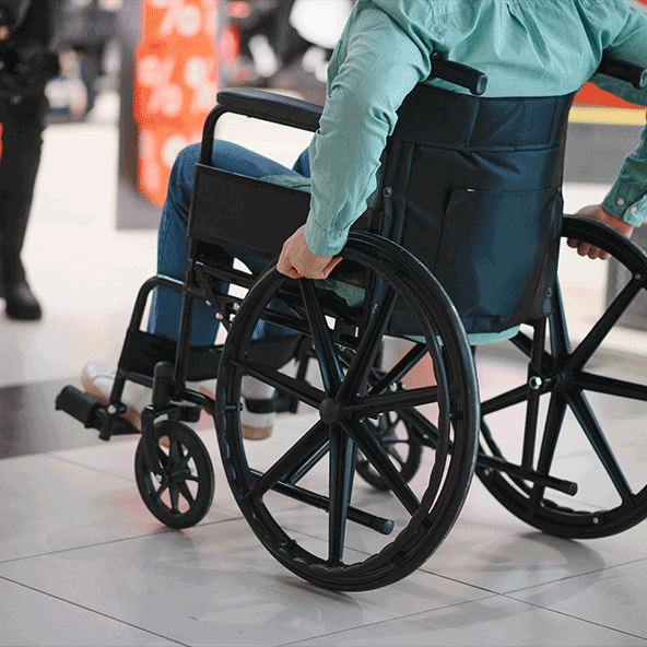 Osoba poruszająca się na wózku inwalidzkim w centrum handlowym, symbolizująca dostępność i mobilność osób niepełnosprawnych