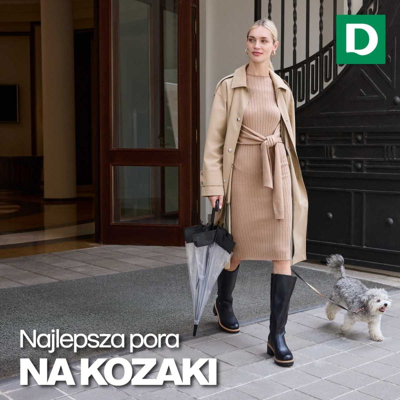 Kobieta ubrana w casualowy płaszcz beżowy i czarne kozaki, w ręku trzymająca parasol.