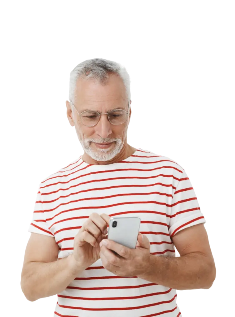 Starszy mężczyzna w siwych włosach i okularach, patrzy na telefon w ręku i przegląda aplikację klubu galerii sudeckiej. Ubrany w tshirt w czerwone paski.